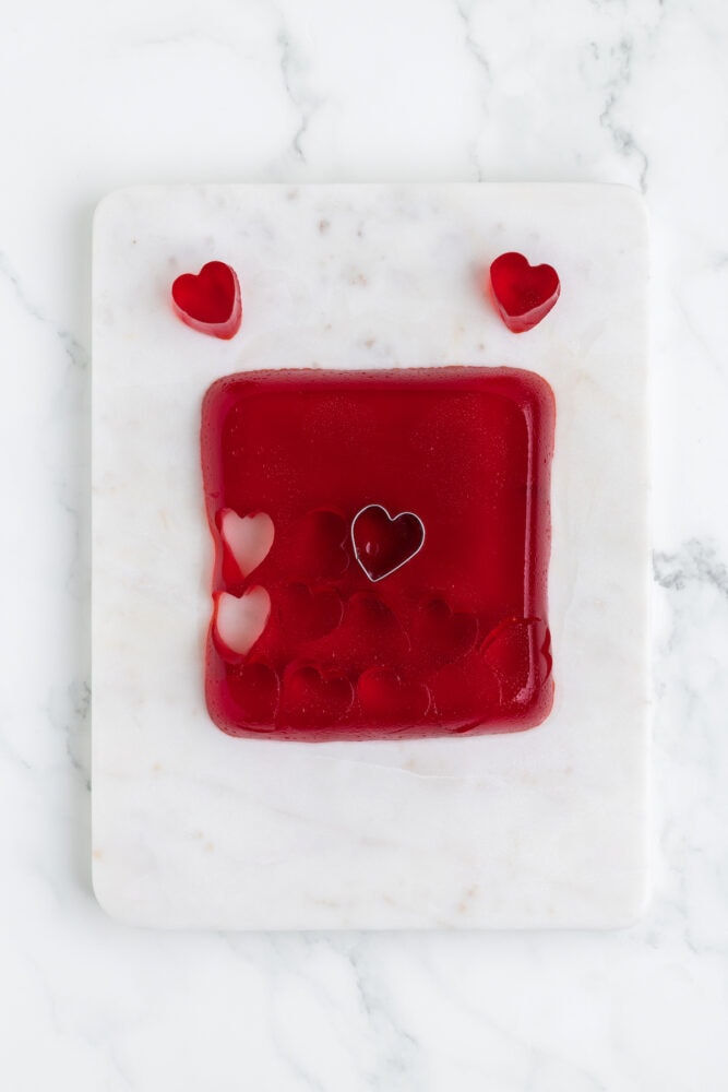 sheet of red jello, hearts being cut out of it