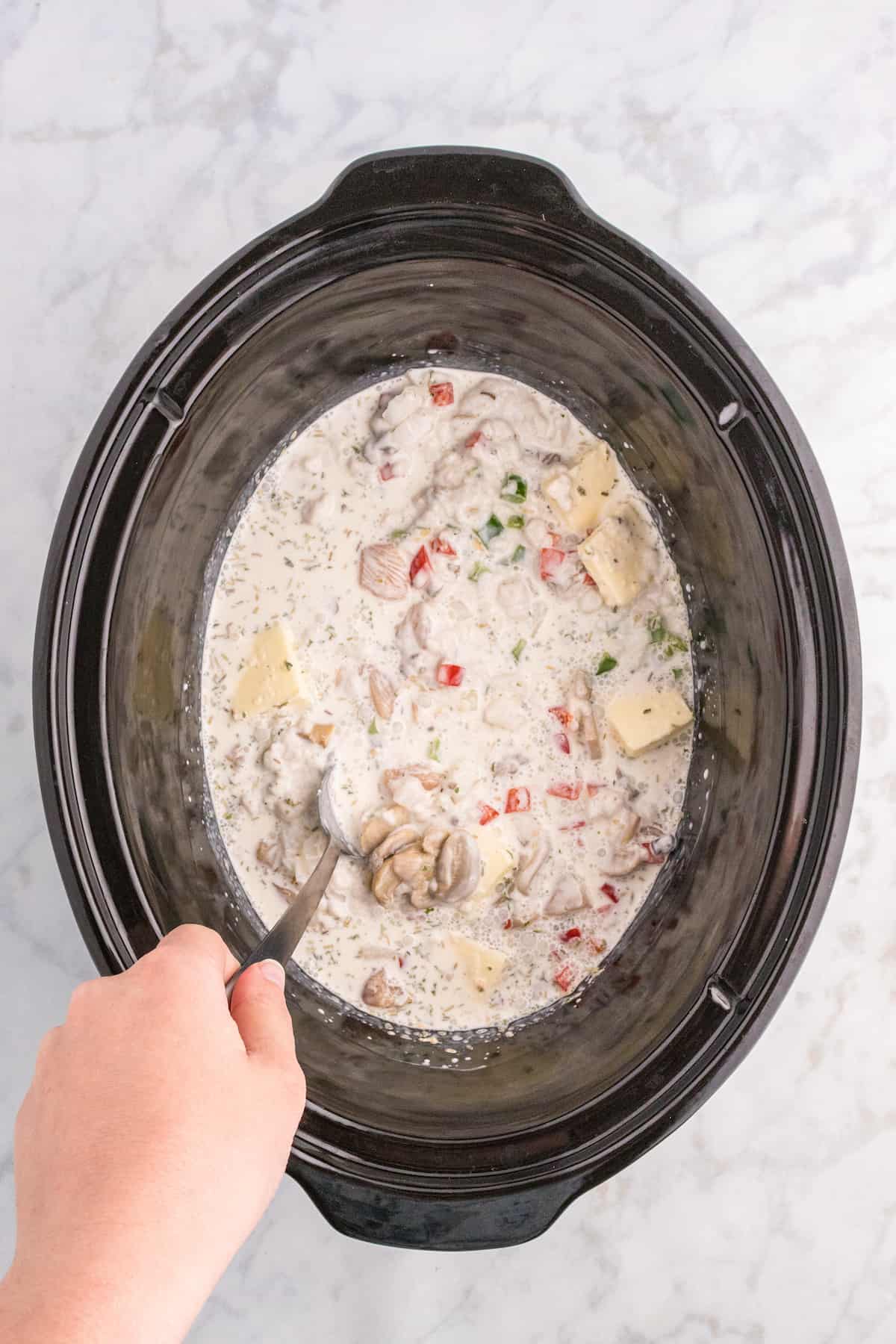 A person pouring Chicken a la King soup into a slow cooker crock pot.